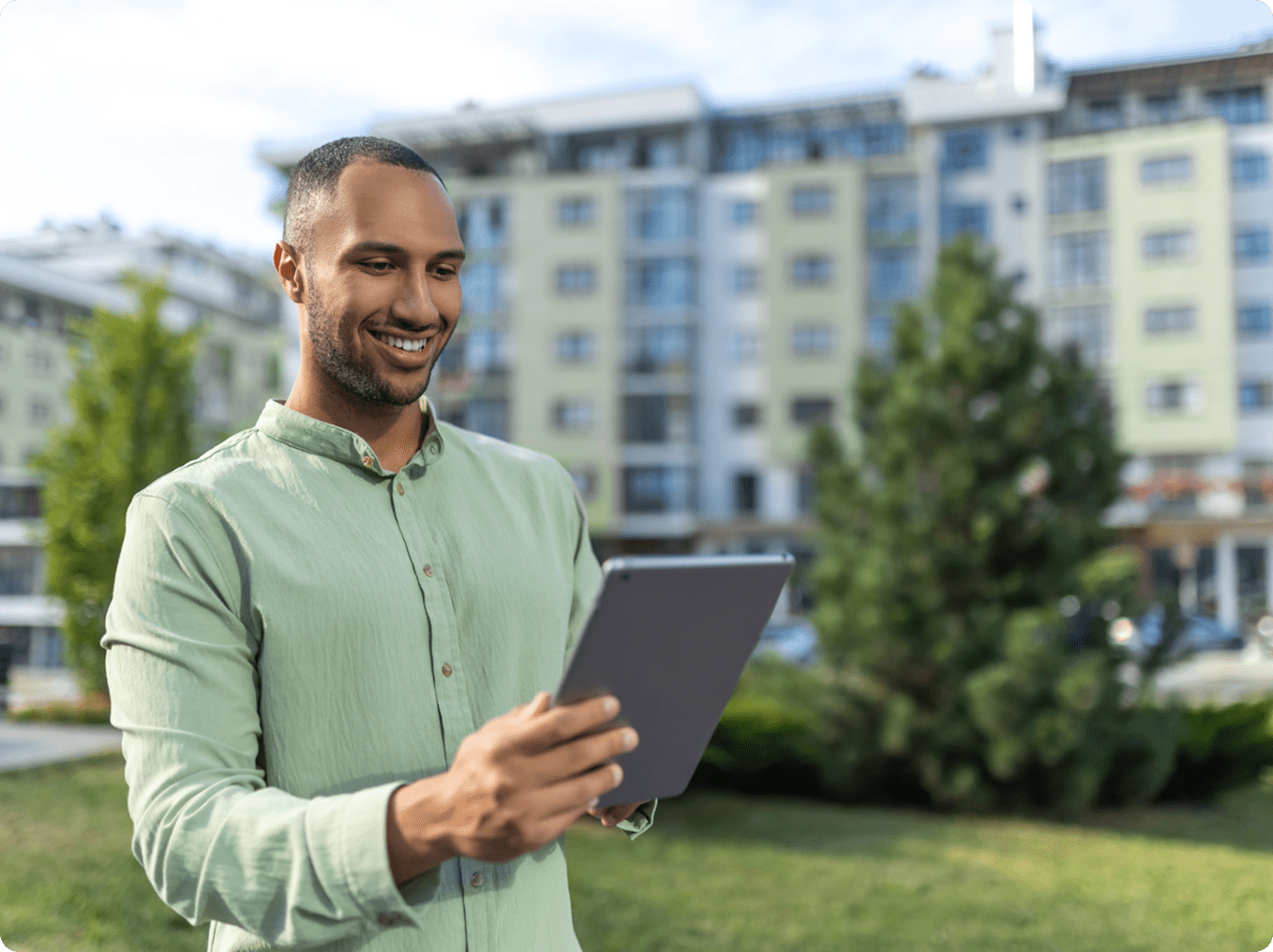 Man smiling while using a tablet outdoors.