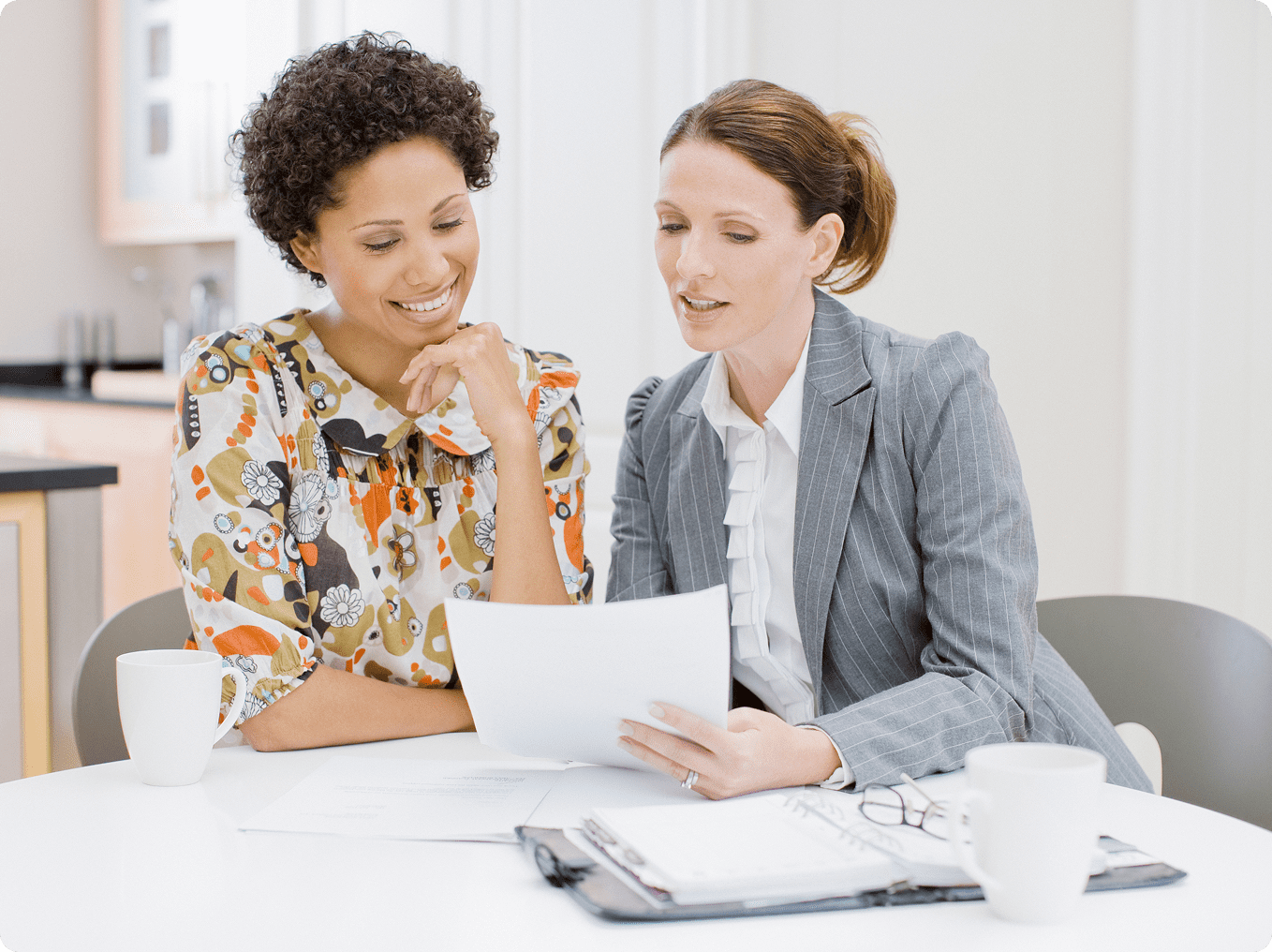 Two women discussing documents at table.